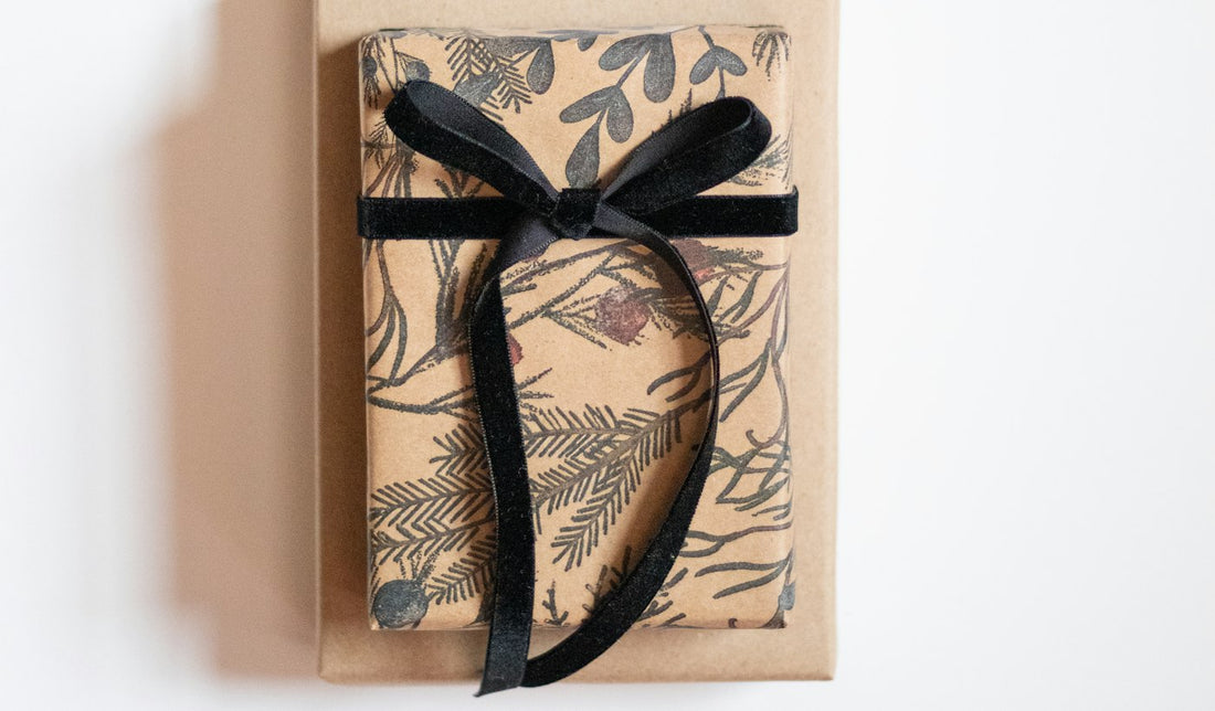 Cadeau élégant emballé avec un ruban noir sur fond de motifs hivernaux