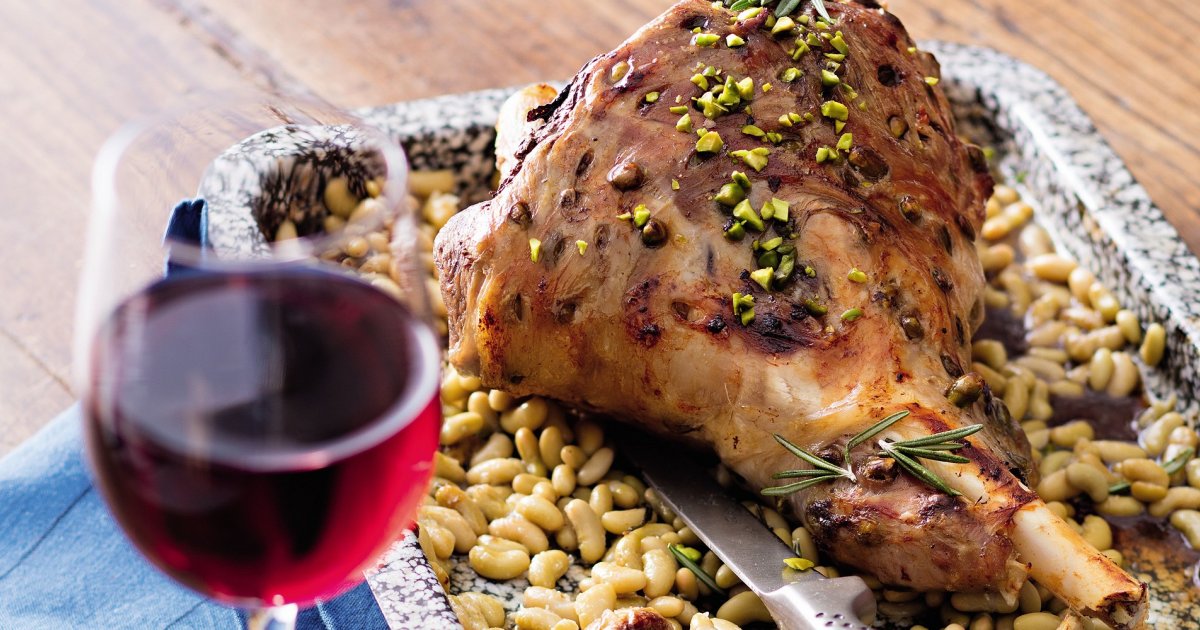 gigot d'agneau rôti tranché présenté avec carafe à décanter et verre de vin rouge