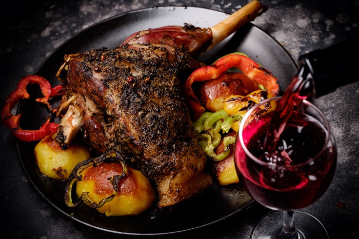 souris d'agneau rôtie accompagnée d'un verre de vin rouge Bordeaux